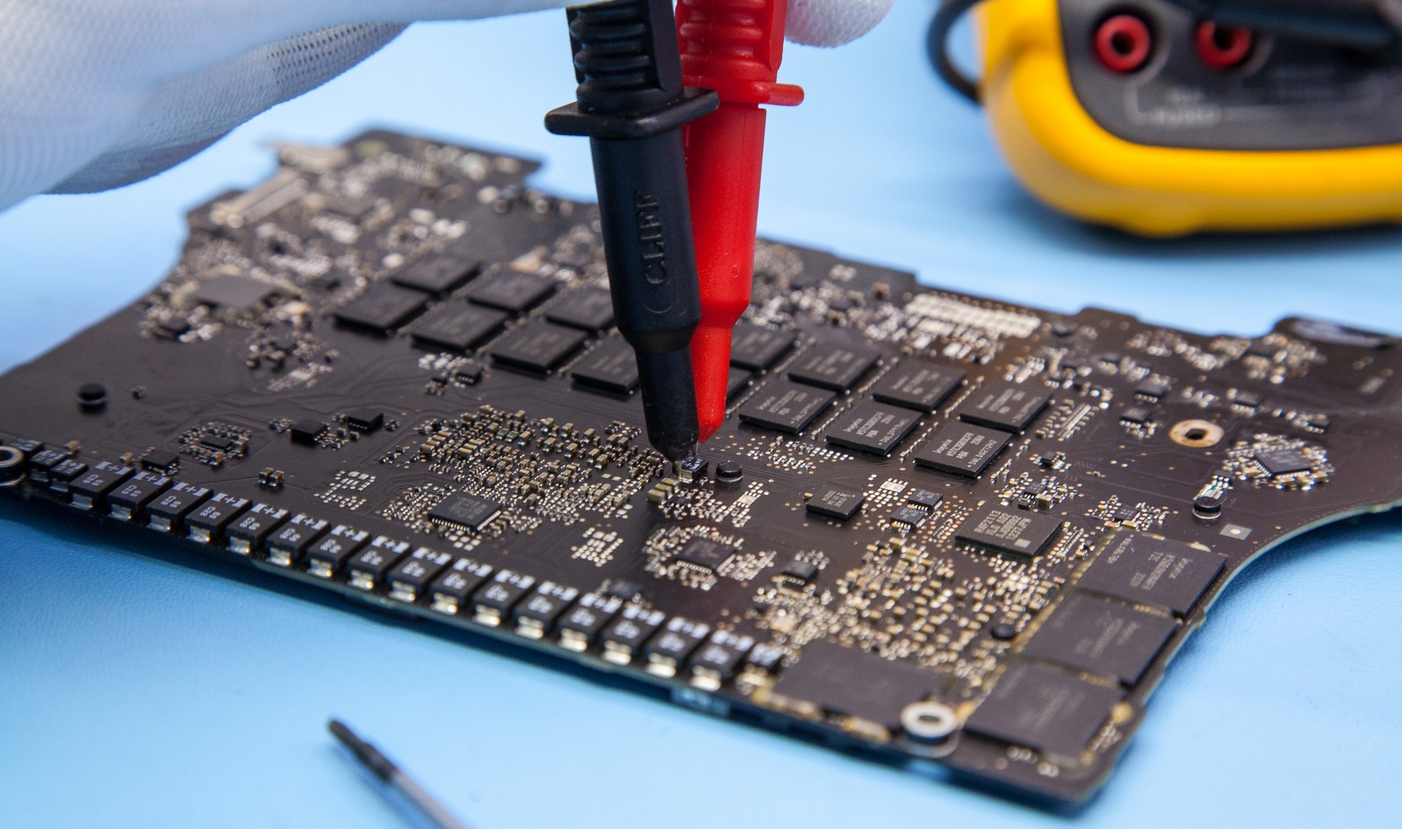 Técnico midiendo una placa madre de notebook durante el diagnóstico electrónico