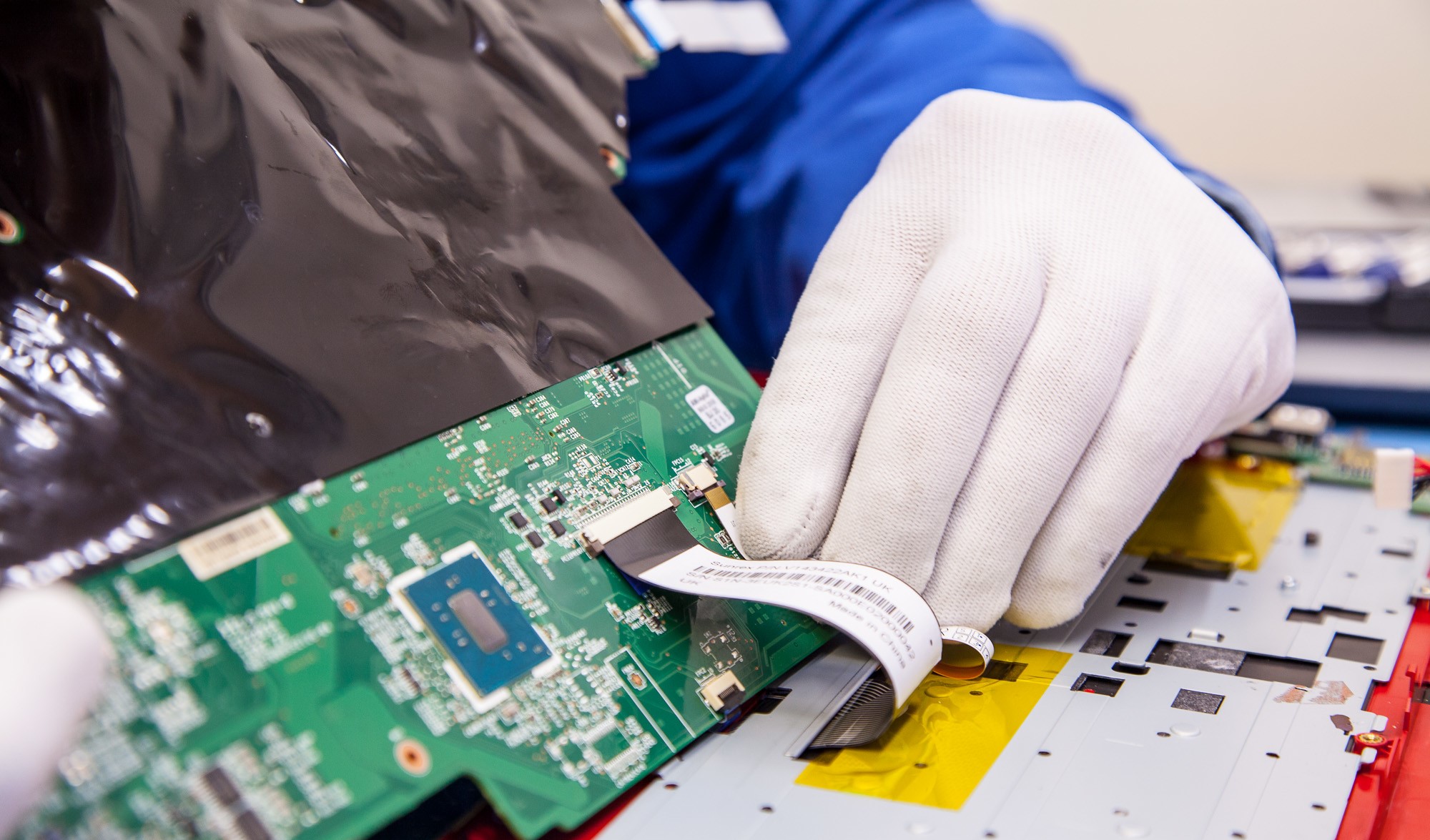 Técnico reparando la placa madre de una notebook abierta en el laboratorio